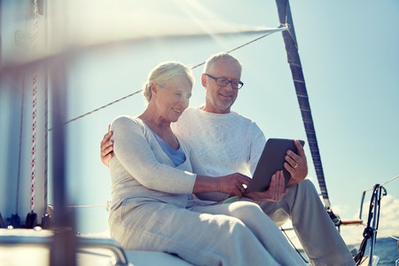 senior couple with tablet pc on sail boat or yachtの写真素材