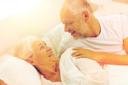 happy senior coupler lying in bad at homeの写真素材