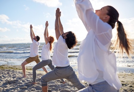 group of people making yoga exercises on beachの写真素材