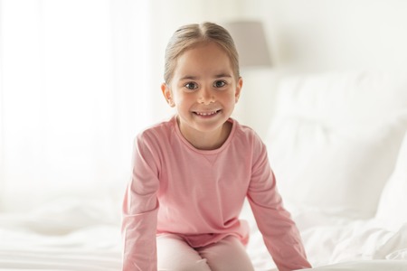 happy little girl on bed at home bedroomの写真素材