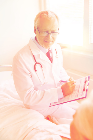 senior woman and doctor with clipboard at hospitalの写真素材