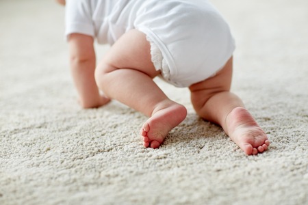 little baby in diaper crawling on floor at homeの写真素材