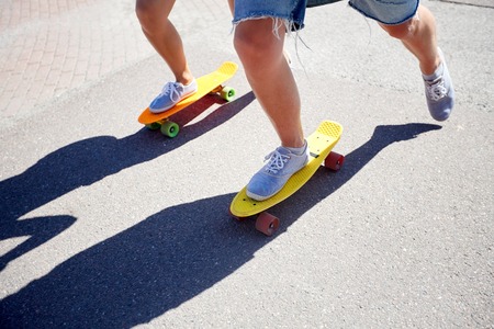 teenage couple riding skateboards on city roadの写真素材
