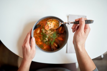 woman eating seafood soup at restaurantの写真素材
