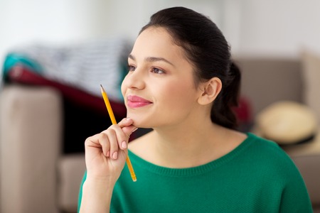 happy young woman with pencil thinkingの写真素材