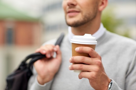 people, drinks and lifestyle - close up of man drinking coffee from disposable paper cup on city streetの写真素材