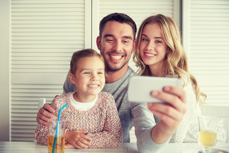 happy family taking selfie at restaurantの写真素材