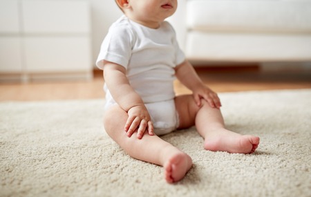 happy baby boy or girl sitting on floor at homeの写真素材