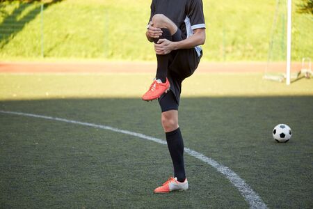 soccer player stretching leg on field footballの写真素材