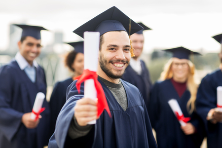 happy students in mortar boards with diplomasの写真素材
