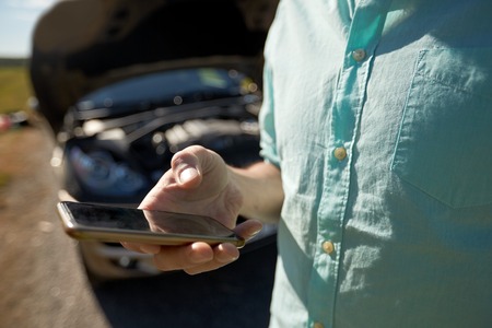 close up of man with smartphone and broken carの写真素材