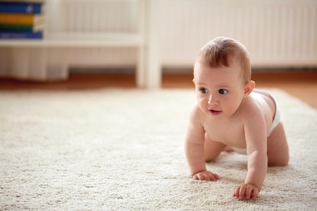 little baby in diaper crawling on floor at homeの写真素材