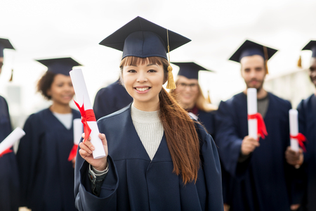 happy students in mortar boards with diplomas