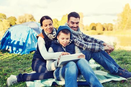 happy family with tablet pc and tent at camp siteの写真素材