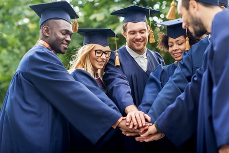 happy students in mortar boards with hands on topの写真素材