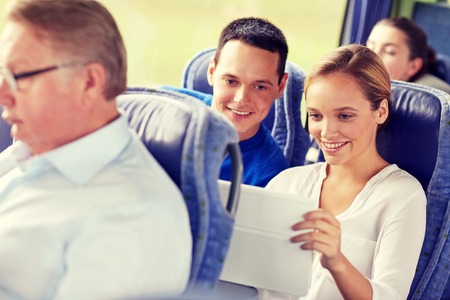 transport, tourism, road trip, technology and people concept - happy couple with tablet pc in travel busの写真素材