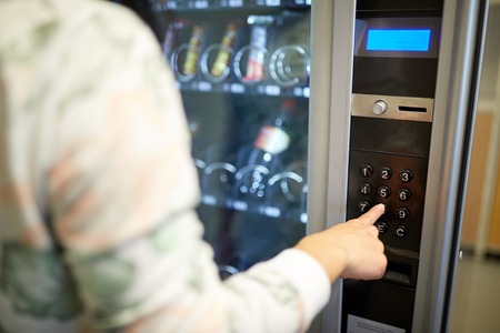 sell, technology and consumption concept - hand pushing button on vending machine operation panel keyboard