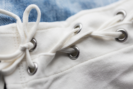 clothes, fashion and objects concept - close up of lacing on clothing item