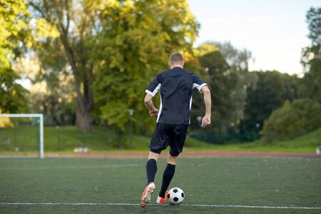 sport, football training and people - soccer player playing with ball on fieldの写真素材