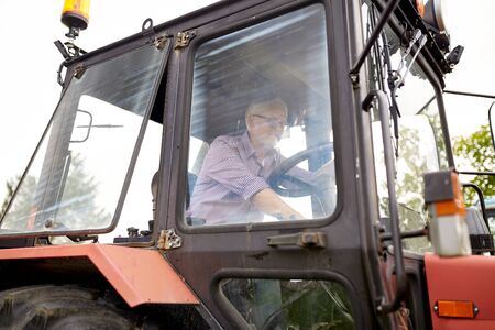 senior man driving tractor at farmの写真素材
