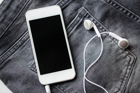 smartphone and earphones on denim or jeans pocketの写真素材