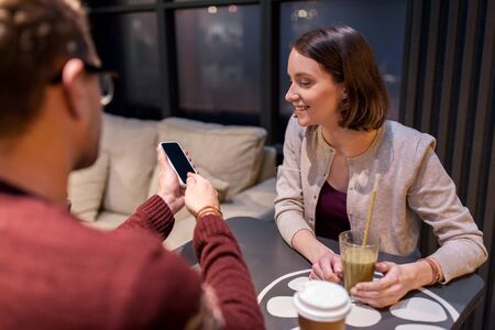 happy couple with smartphone and drinks at cafeの写真素材