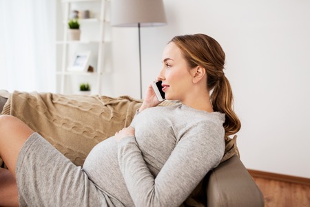 happy pregnant woman calling on smartphone at home
