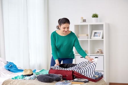 woman packing travel bag at home or hotel roomの写真素材