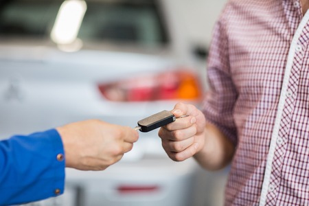 auto mechanic giving car key to man at workshop
