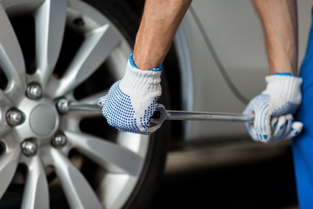 mechanic with screwdriver changing car tireの写真素材