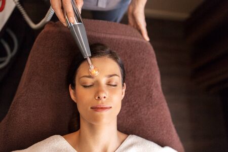 woman with microcurrent face massager in spa