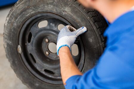 mechanic with wheel tire at car workshopの写真素材