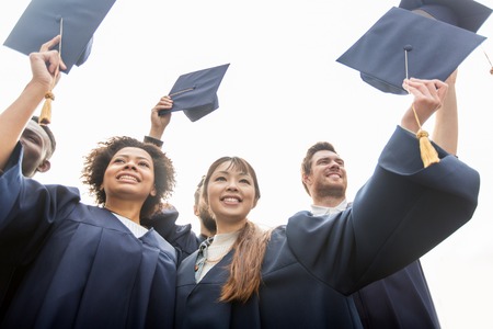 happy students or bachelors waving mortar boardsの写真素材