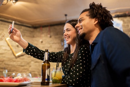 happy couple taking selfie at cafe or barの写真素材