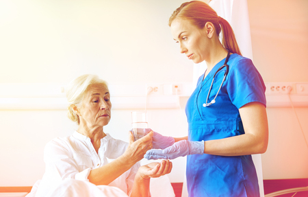 nurse giving medicine to senior woman at hospitalの写真素材