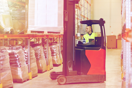 man with tablet pc operating forklift at warehouseの写真素材