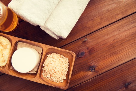 beauty, spa, body care, natural cosmetics and wellness concept - close up of soa with himalayan pink salt and bath towels on wooden tableの写真素材