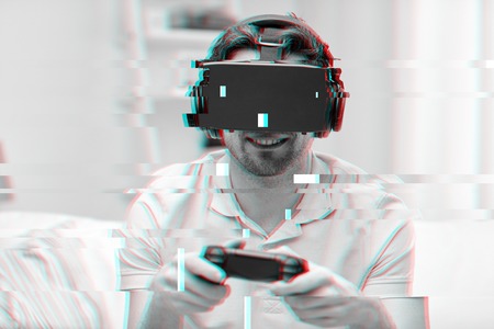 technology, gaming, entertainment and people concept - happy young man with virtual reality headset...