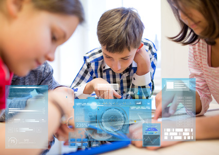 education, elementary school, learning, technology and people concept - group of kids with tablet pc computers in classroom over virtual screens projectionsの写真素材