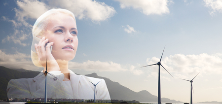businesswoman with smartphone over wind turbinesの写真素材
