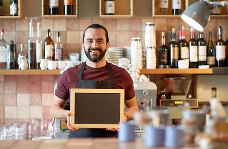 happy man or waiter with chalkboard banner at barの写真素材