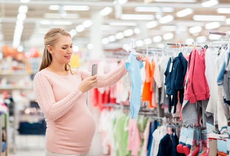 pregnant woman taking picture of baby clothesの写真素材