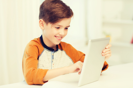 smiling boy with tablet pc computer at homeの写真素材