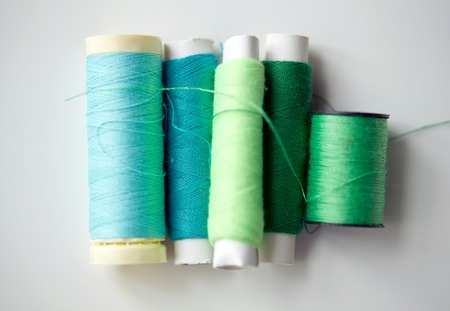 green and blue thread spools on tableの写真素材