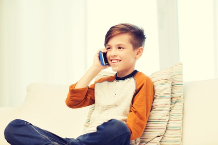 leisure, children, technology, communication and people concept - smiling boy calling on smartphone...