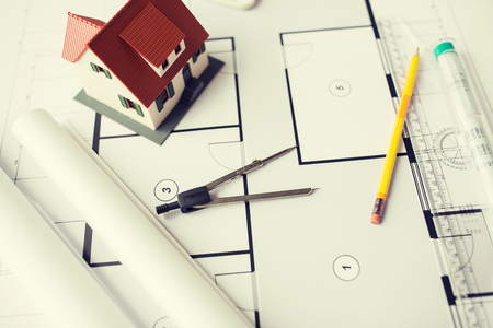 architecture, building, construction, real estate and home concept - close up of blueprint with living house model and toolsの写真素材