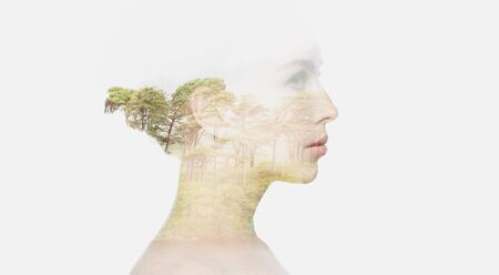 people, nature and beauty concept - beautiful young woman face with natural double exposure effect over white backgroundの写真素材