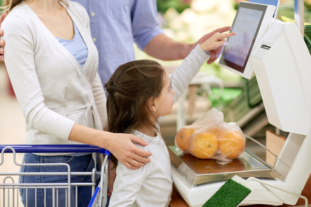 shopping, sale, consumerism and people concept - happy family with child weighing oranges on scale at grocery storeの写真素材