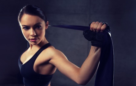 fitness, sport, training, people and lifestyle concept - woman doing exercises with expander or resistance band in gymの写真素材