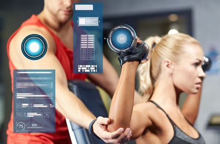 sport, fitness, bodybuilding and people concept - man and woman with dumbbells flexing muscles in gym over virtual chartsの写真素材